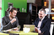 © Denizo - Two smiling business men eat at restaurant