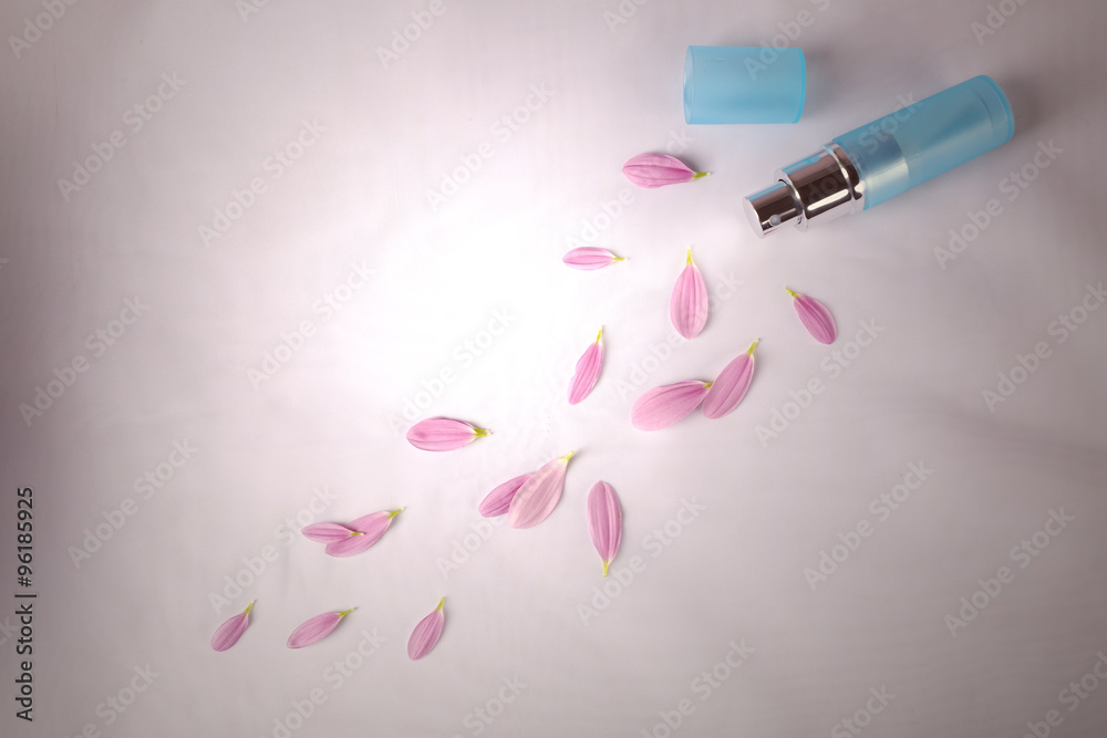 Bottle of perfume and rose petals on fabric background