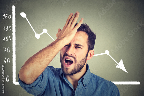 Fotomural frustrated stressed young man desperate with financial market chart graphic goin