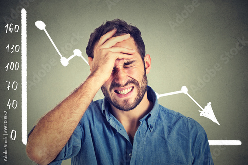 Fotografía frustrated stressed young man desperate with financial market chart graphic goin