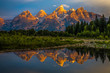 The dramatic colors of the Grand Teton Mountains reflecting in the water on a clear summer morning. 