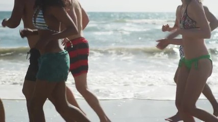 Wall Mural - Young Adult Group of interracial friends running along beach shore waves 