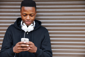 Teenage Boy Listening To Music And Using Phone In Urban Setting