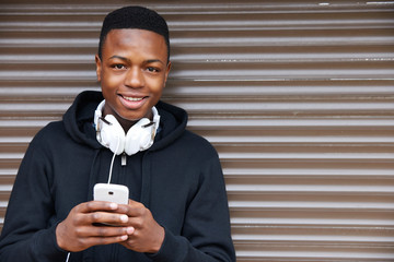 teenage boy listening to music and using phone in urban setting