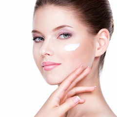 Wall Mural - Beauty face of young woman with cosmetic cream on a cheek.