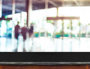Fototapete - Empty black marble table top and blurred people in building corr