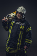 Firefighter in helmet holds oxygen tank.