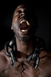 Bare chested black man, screaming out and holding a large heavy chain around his neck.