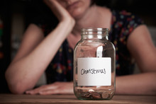 Depressed Woman Looking At Empty Jar Labelled Christmas