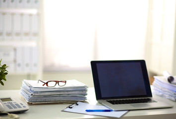 Office table with blank notepad and laptop 