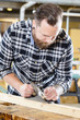 © kjekol - Carpenter work with planer on wood plank in workshop