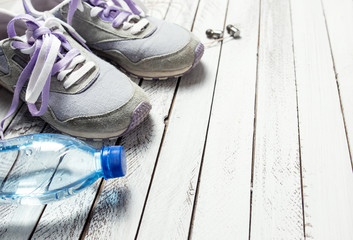 Pair of sport shoes, water bottle and earphones on white wooden