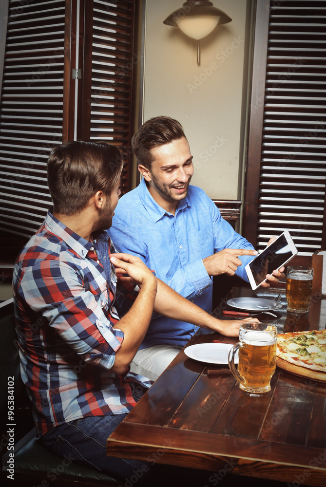 Young men drinking beer and talking in cafe