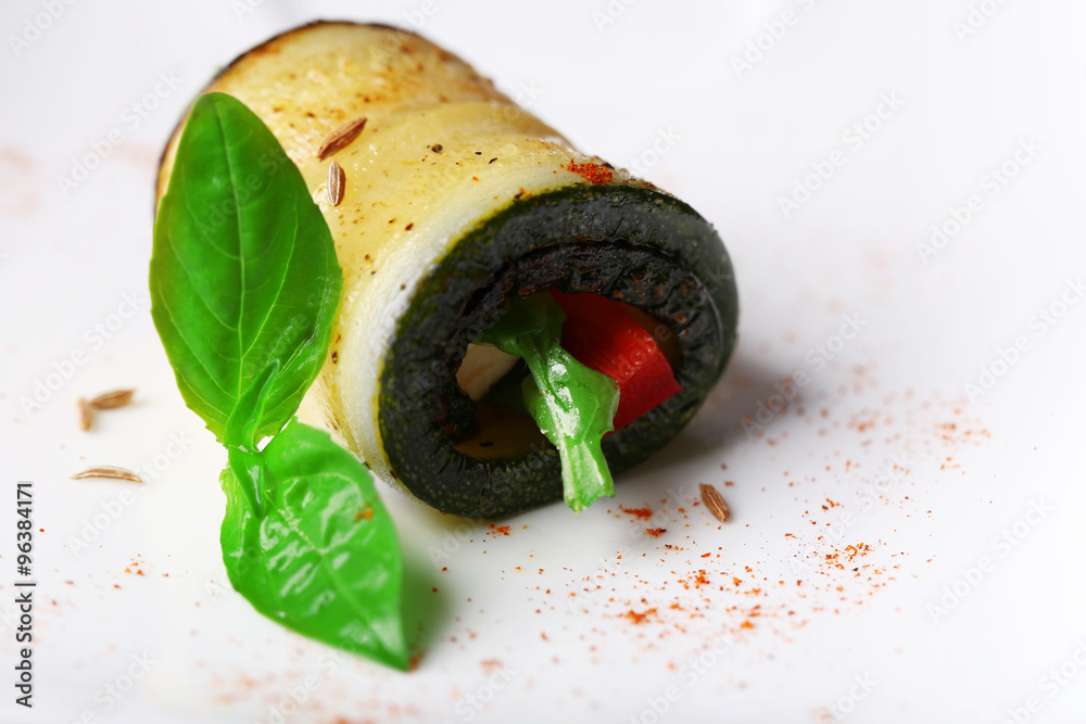 Zucchini roll with cheese, bell peppers and arugula on plate, close-up