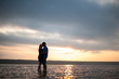 Loving couple embracing by the sea at sunset