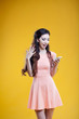 © Ulia Koltyrina - Fashion asian young  girl with mobile phone, in shock. Portrait on yellow background
