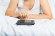 © volkovslava - Young woman in bed with a calculator. Family budget. Credit,