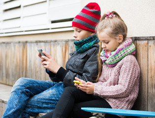 Wall Mural - Positive siblings playing with phones on street