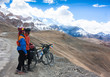 © lkoimages - Happy cyclist couple standing on mountains road. Himalayas, Jammu and Kashmir State, North India