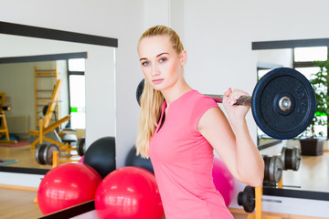 Young woman lifting a barbell in the gym