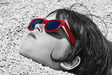 boy buried in the pebbles on the beach