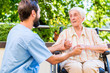 Pfleger hält Hand von Seniorin im Seniorenheim
