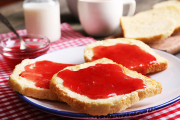 Wall Mural - Bread with butter and homemade jam in white plate on red checkered napkin, closeup