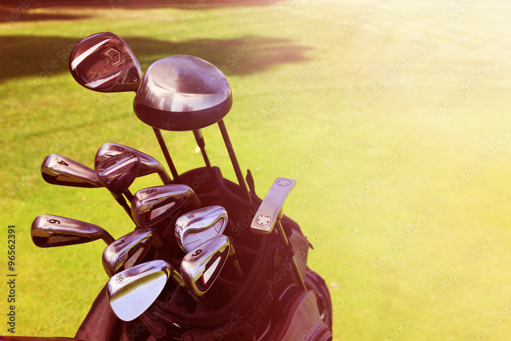 Golf bag with clubs on green field, close up