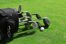 Golf Bag With Clubs And Balls On Green Field, Close Up