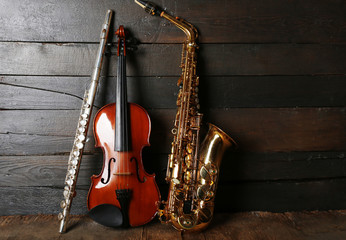 Musical instruments: saxophone, violin and flute on wooden background