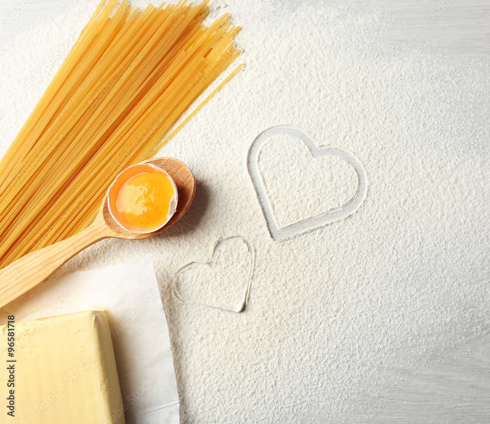 Heart of flour and pasta on gray background
