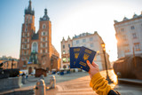 Fototapeta Big Ben - Female hands holding Ukrainian abroad passports on the Krakow city center background