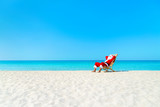 Fototapeta Przestrzenne - Christmas Santa Claus resting on sunlounger at ocean sandy tropical beach