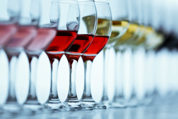 Wall Mural - Wineglasses with white, red and pink wine on wooden table on bright background