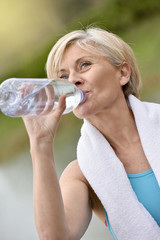  Senior woman drinking water after exercising
