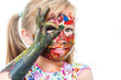 © karelnoppe - Little girl with painted face peeping through finger hole.