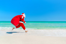 Santa Claus Running Along Beach With Sack Full Of Gifts