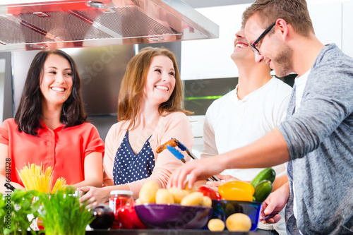 Obraz na plátně Freunde kochen Spagetti und Fleisch zuhause in Küche