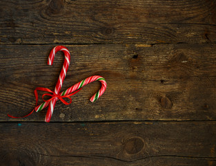 Closeup of two old fashioned candy canes on a rustic wooden back