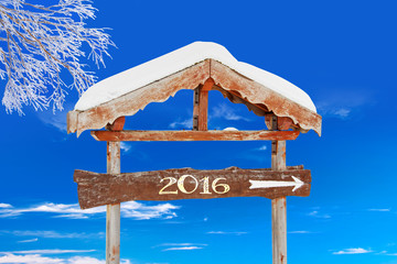 Wall Mural - 2016 written on a wooden direction sign, blue sky and frozen tree background
