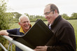 © Mint Images - Two men standing looking over a farm gate, one with an open file and paperwork.
