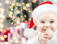 Happy Baby In Santa Hat Over Christmas Lights