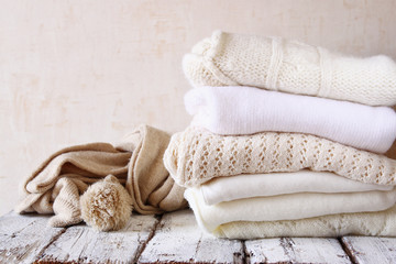 Stack of white cozy knitted sweaters on a wooden table
