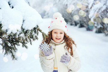 Wall Mural - Laughing girl with snowflakes in his hand, in winter park.