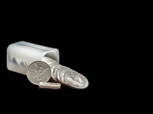 Modern And Antique Silver Dollars Spilling Out Of A 
Treasury Coin Holder Onto A Black Background With A One Troy Ounce Silver Bar.