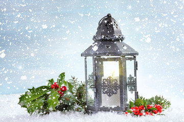 Christmas lantern with Holly leaves and berries on a snowy backg