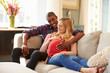 © Monkey Business - Pregnant Couple At Home Relaxing On Sofa Together
