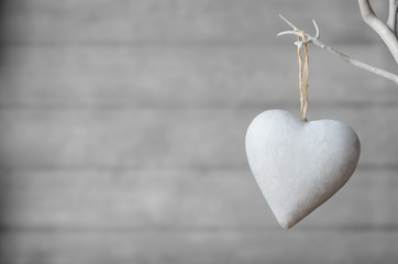 white heart hanging from tree on wood background
