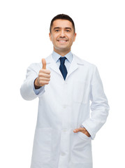 Wall Mural - smiling doctor in white coat showing thumbs up