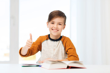 Wall Mural - happy student boy with textbook showing thumbs up